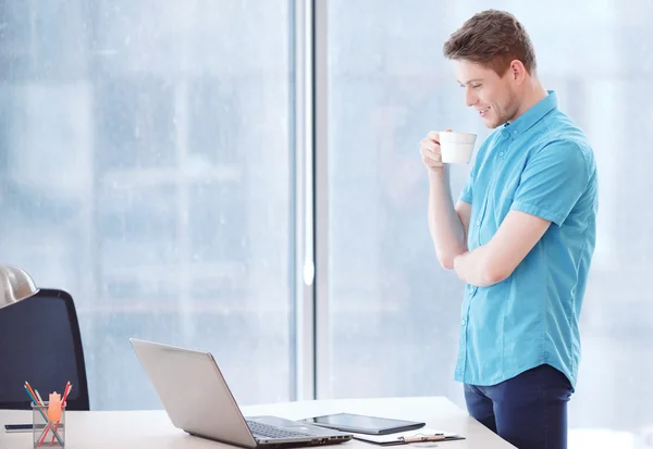 Jeune homme d'affaires debout à côté du bureau — Photo