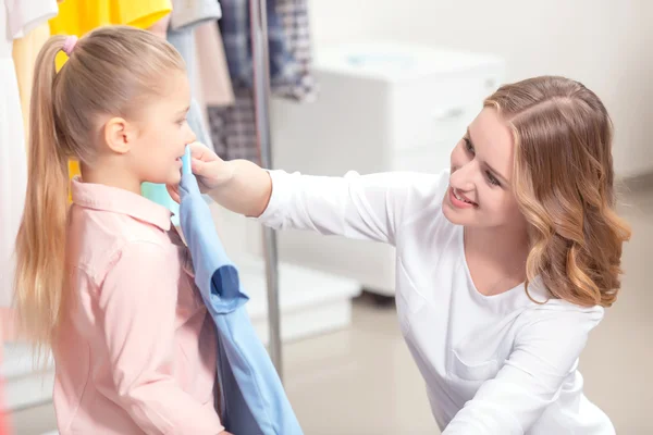 Jeune mère attachant sur la robe sa petite fille — Photo