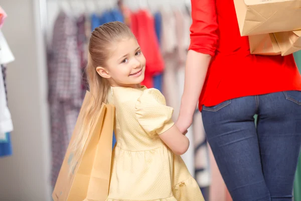 Happy mother with her daughter and lots of new purchases in pack — Stock Photo, Image