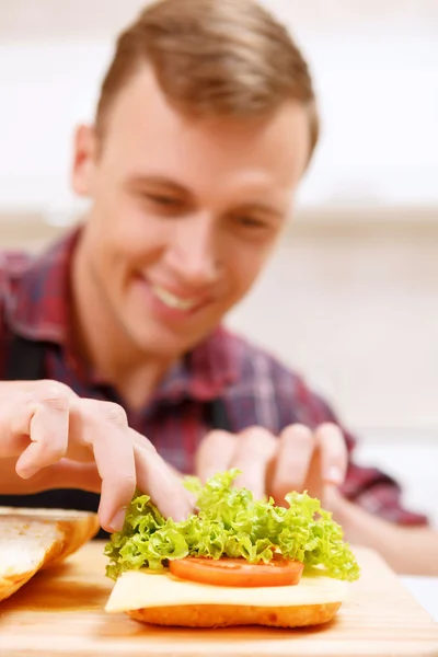 Close up of man decorating bread with lettuce — Stock Photo, Image