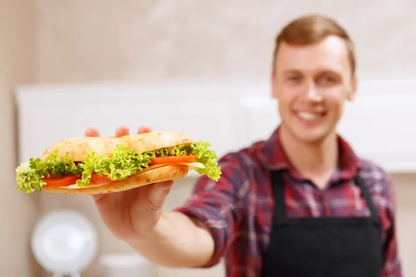 Lächelnder Mann zeigt fertig gebackenes Sandwich — Stockfoto
