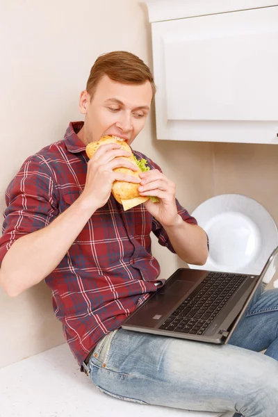 Man eating sandwich and holding notebook — Stock Photo, Image