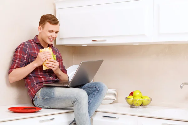 Man holding sandwich and looking at computer screen — Stock Photo, Image