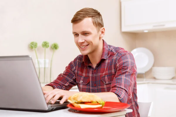 부엌에 있는 컴퓨터에서 작업 하는 웃는 남자 — 스톡 사진