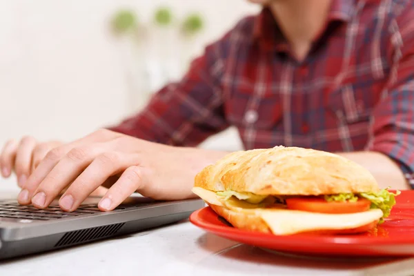 Close up of sandwich on plate and typing man — Stock Photo, Image