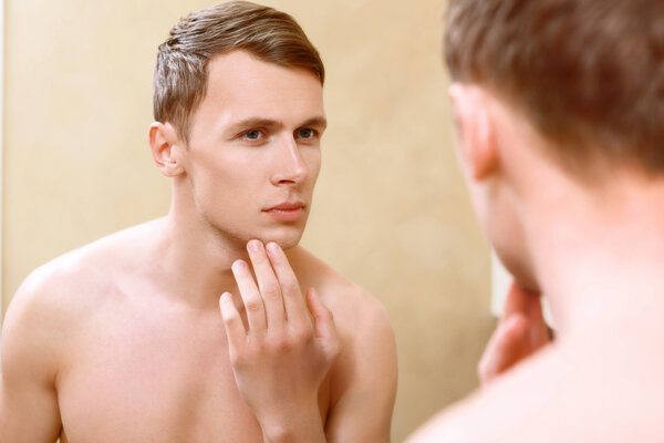 Мужчина топлесс касается его лица пальцами
