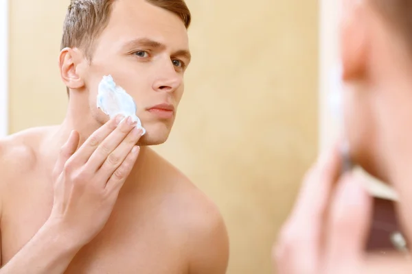 Hombre en topless aplicando medio de afeitarse en la cara — Foto de Stock