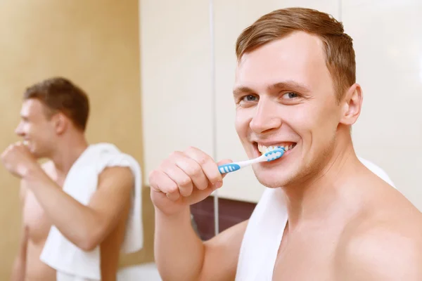 Seorang pria membersihkan gigi di depan cermin — Stok Foto