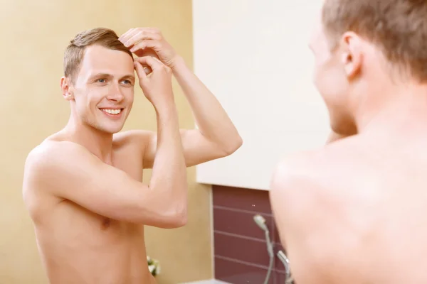 Oben-ohne-Mann fixiert seine Haare im Badezimmer — Stockfoto