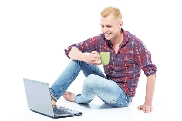 Молодий чоловік сидить на підлозі з кавою — стокове фото