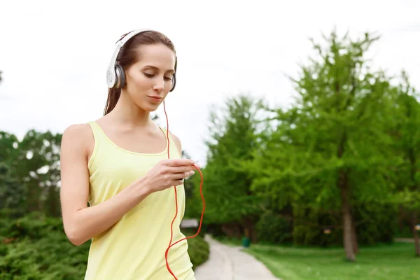 Молодая спортсменка выбирает музыку в парке — стоковое фото