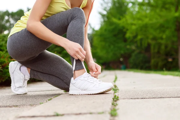 Woman lacing her shoes in park — Stock Photo, Image