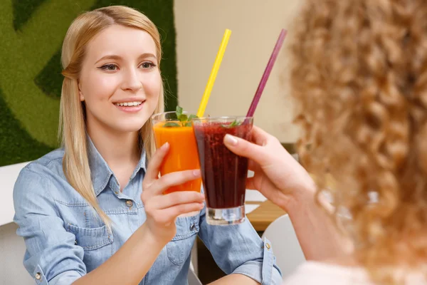 Two women clinking glasses with cocktails in cafe — Stock Photo, Image