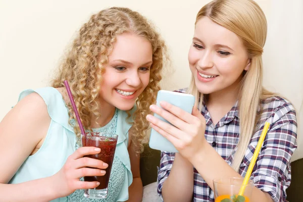 Pair of women looking at phone in cafe — Stock Photo, Image