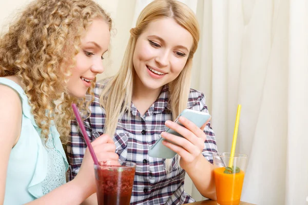 Pair of women looking at phone in cafe — Stock Photo, Image