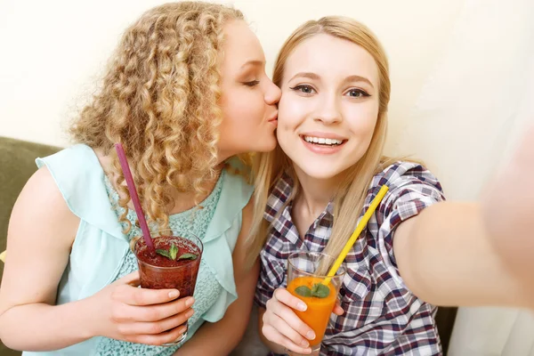 Two smiling girls doing selfie in cafe — Stock Photo, Image