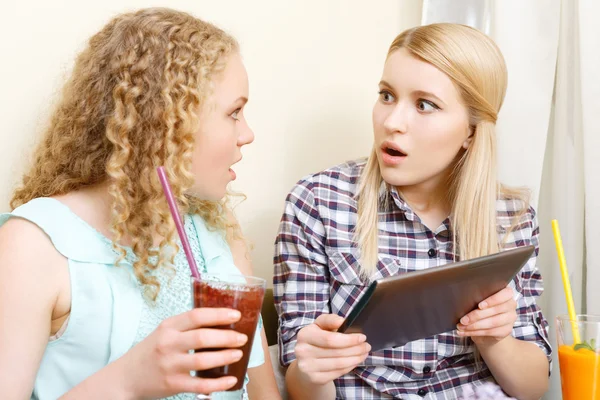 Två förvånad tjejer med tabletten i café — Stockfoto