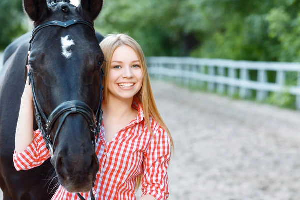 Smiling girl taking care of the horse — Stock Photo, Image