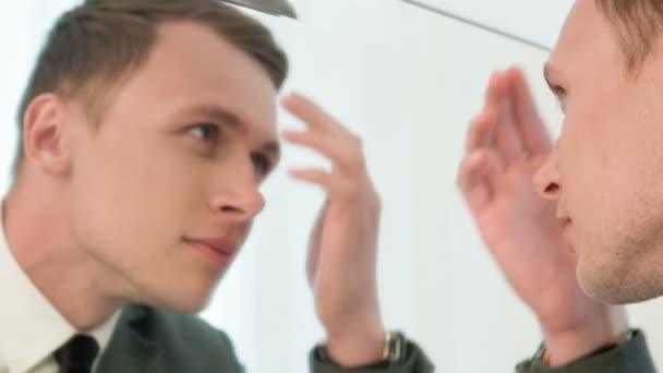 거울 앞에서 그의 머리를 고정 하는 젊은 남자 — 비디오