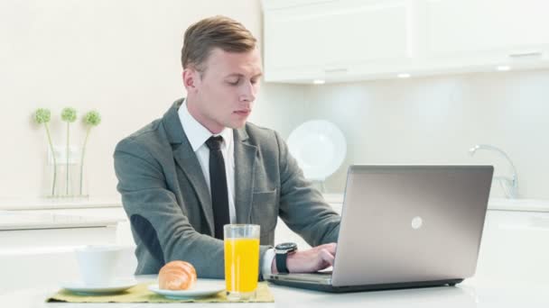 Hombre de traje trabajando en la computadora en la cocina — Vídeo de stock