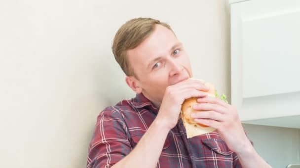 Hombre comiendo sándwich delante de la computadora — Vídeo de stock