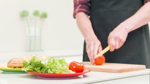 Schöner Mann schneidet Tomaten in der Küche — Stockvideo