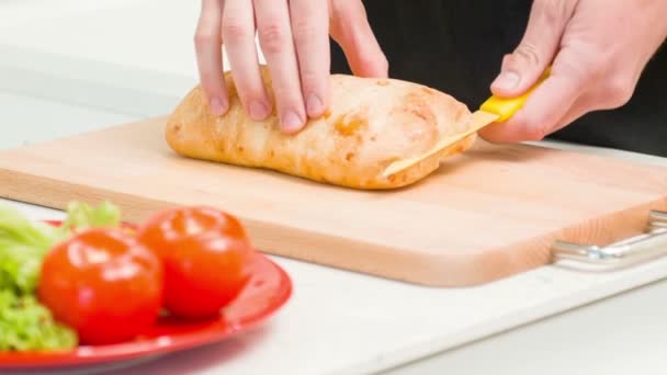 Bonito jovem cortando pão na cozinha — Vídeo de Stock