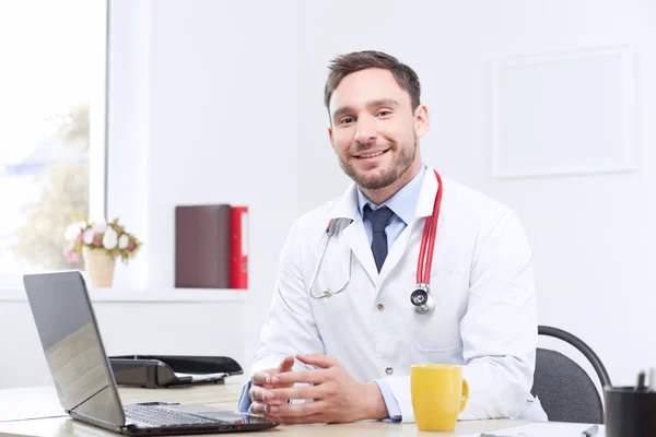 Lachende cardioloog zitten aan de tafel — Stockfoto