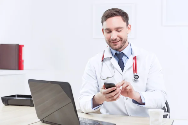 Улыбающийся кардиолог держит мобильный телефон — стоковое фото
