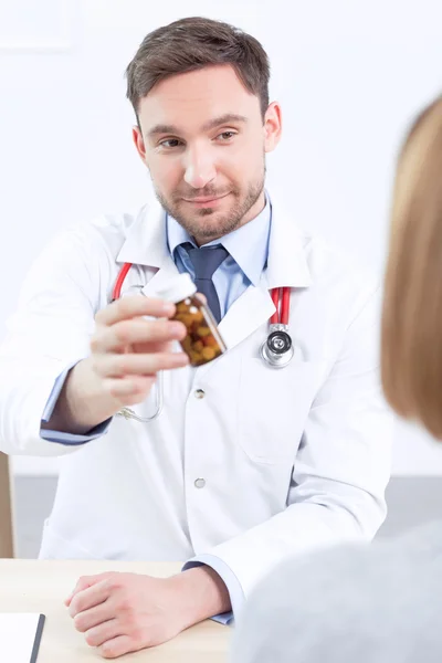 Улыбающийся кардиолог дает пациенту таблетки — стоковое фото