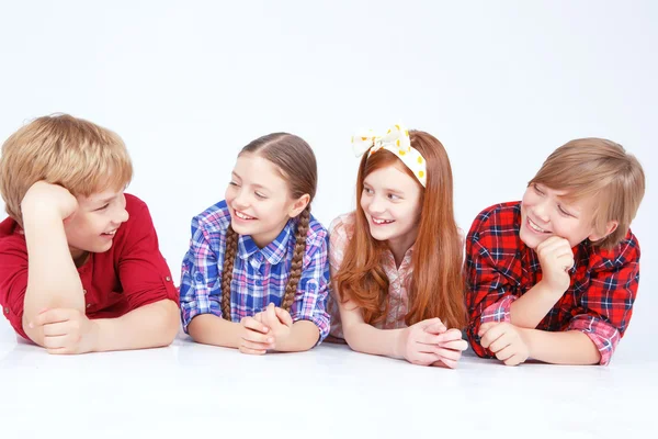 Smiling children lying on the floor in raw — Stock Photo, Image