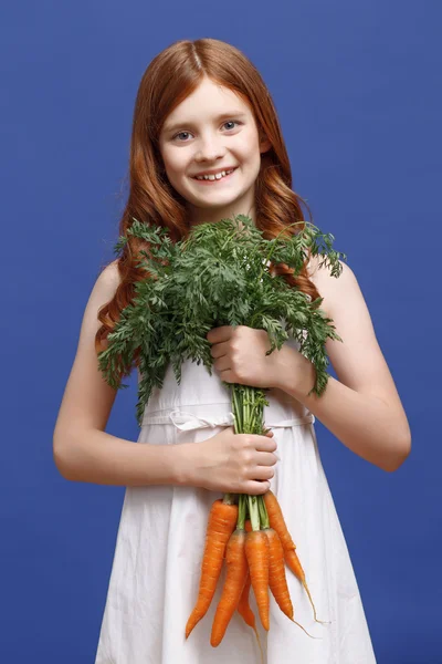 Leende flicka håller massa morötter — Stockfoto
