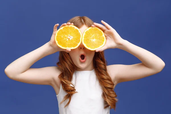 Leende flicka håller halvorna av orange — Stockfoto