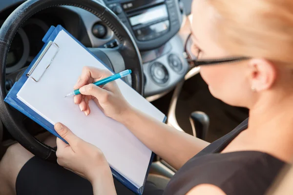 Woman sighing papers inside car — Stock Photo, Image