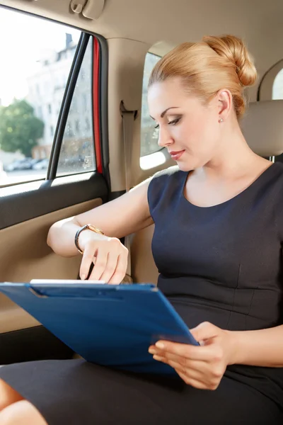 Affärskvinna kontrollera tid i bil — Stockfoto