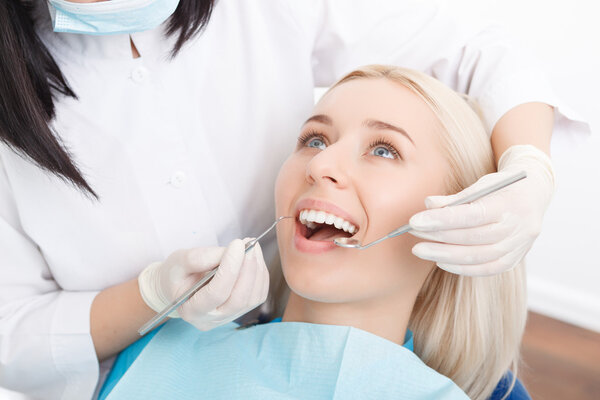 Женщине проверяют зубы у дантиста
 