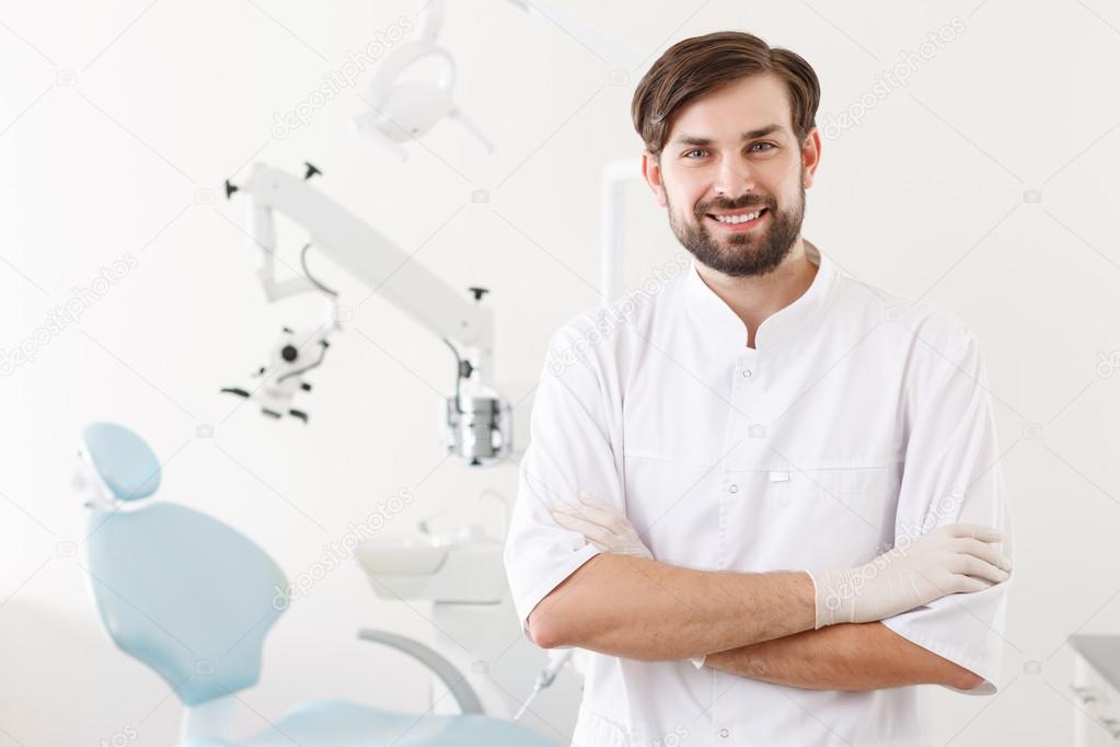 Portrait of young handsome dentist in clinic