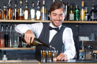 Handsome bartender making shots