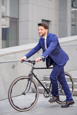 Pleasant businessman standing with bicycle 