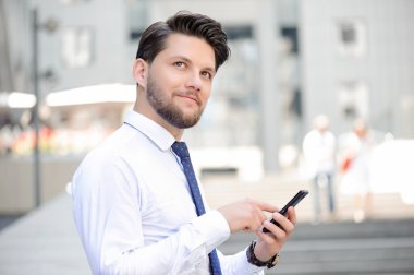 Nice young businessman holding mobile phone