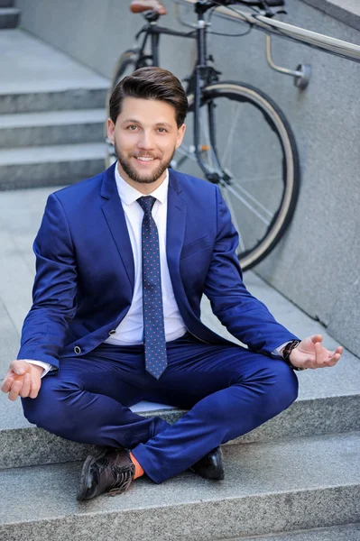 Young businessman practicing yoga on stairs