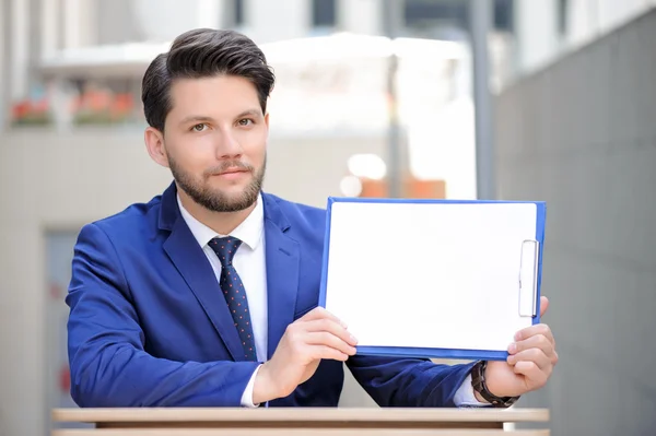 Angenehmer Mann sitzt mit Papieren am Tisch. — Stockfoto