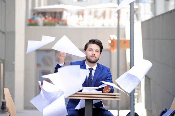 Un hombre serio tirando papeles. — Foto de Stock