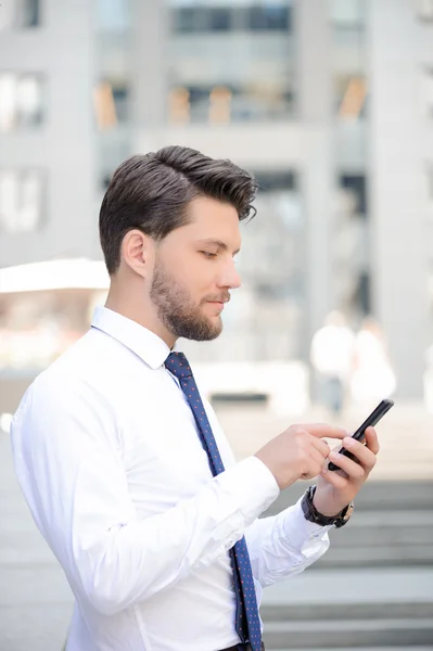 Nice young businessman holding mobile phone — Stockfoto