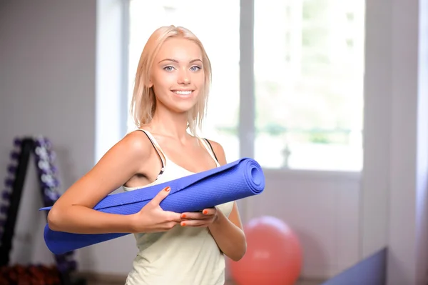 Mujer con esterilla de yoga azul en sus manos , — Foto de Stock