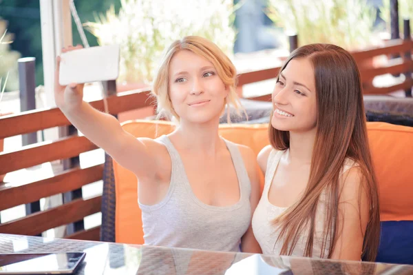 Dwie dziewczyny robienie selfie w kawiarni — Zdjęcie stockowe