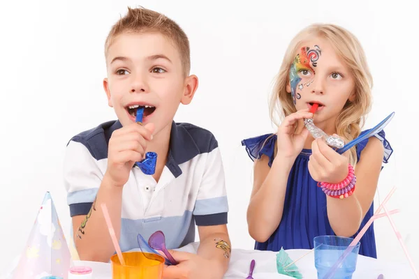 Pleasant children blowing birthday pipes — Stock Photo, Image