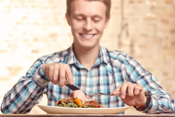 Handsome man eating salad in cafe — Stock Photo, Image