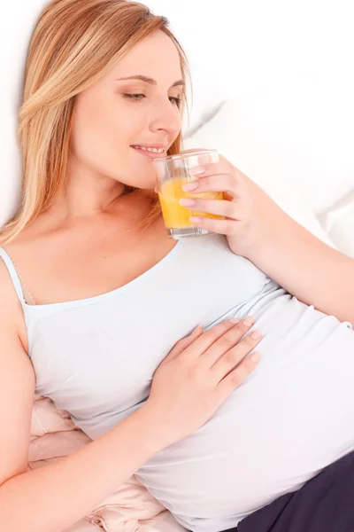 Беременная женщина пьет апельсиновый сок — стоковое фото