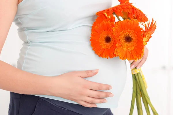 Mujer embarazada sosteniendo flores — Foto de Stock